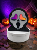 Absolute Prints black and white Ghostface mask display piece on a white circular base with Halloween decor background