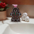Absolute Prints gingerbread man liquid soap dispenser with a pink pump, featuring icing details on a bathroom vanity.